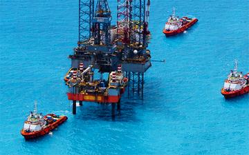 Oil rig in clear blue water, connected with offshore marine internet, surrounded by 3 boats 